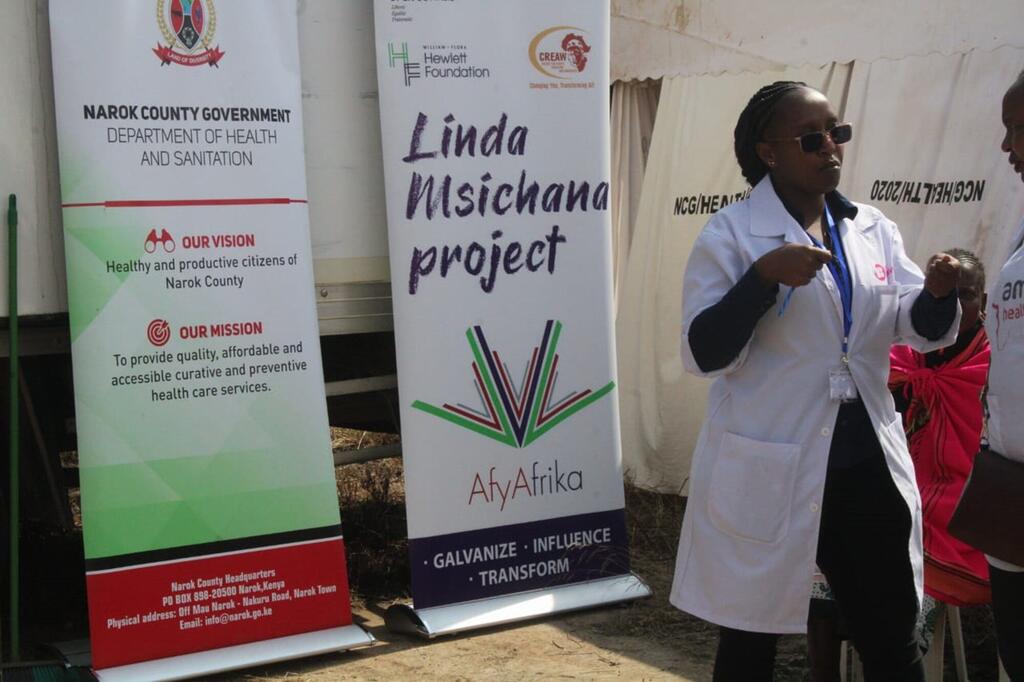 Mtaalamu wa matibabu katika kanzu nyeupe akizungumza katika tukio huko Narok, Kenya, akiendeleza mradi wa Linda Msichana, ambao unakusudia kukomesha ukataji wa viungo vya uzazi wa kike (FGM) kwa msaada wa UNFPA na AfyAfrika.