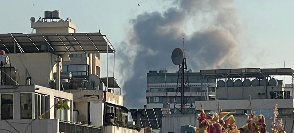 A large plume of smoke rises over the urban skyline of Beirut, Lebanon, near UNIFIL positions, indicating an explosion or ongoing conflict.