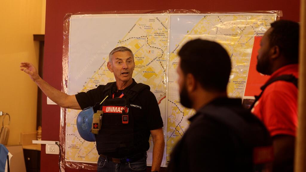 جويل فورنييه (إلى اليسار)، كبير مستشاري الأمن الميداني في مكتب الأمم المتحدة لخدمات المشاريع، ودائرة الأمم المتحدة للإجراءات المتعلقة بالألغام (أونماس). مستشار اليوناماس في غزة يقدم تقريرا أمام خريطة غزة.