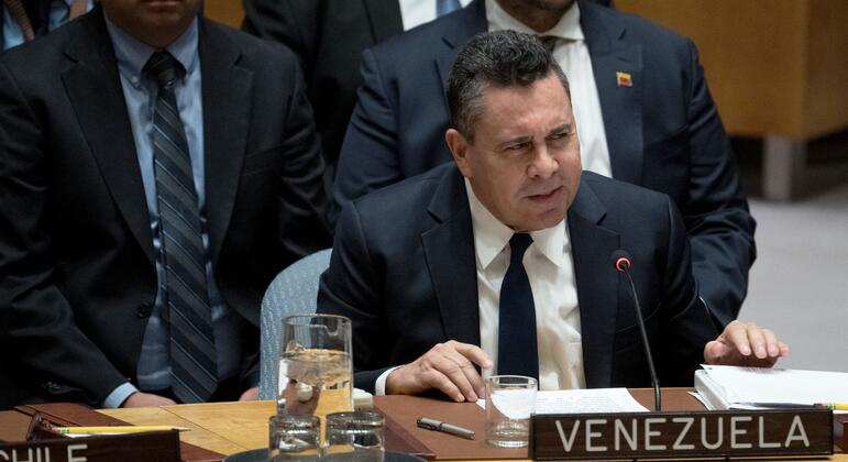 Венесуэльский дипломат, выступающий на заседании Организации Объединенных Наций, с надписью "Венесуэла" на столе.