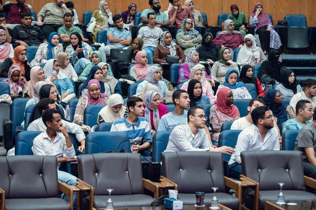 Watazamaji wa watu mbalimbali, wengi wakiwa wamevaa kofia, wanasikiliza kwa makini maonyesho kuhusu kukomesha ukataji wa viungo vya uzazi wa wanawake nchini Misri, ikiangazia upinzani na maendeleo ya jamii.