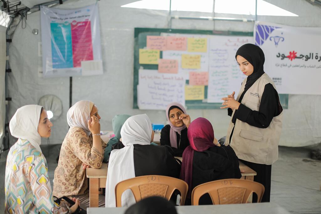 متطوعة شابة من صندوق الأمم المتحدة للسكان تقود جلسة تعليم جنسي شامل للفتيات المراهقات في مبادرة خيمة الفتيات في غزة.