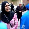 امرأة ترتدي حجابًا أسودًا وستويتر وردي تتحدث مع شخص يرتدي سترة زرقاء، من المحتمل أن يكون عاملًا في المفوضية السامية للأمم المتحدة لشؤون اللاجئين، في بيروت، لبنان. تم تشريدها من جنوب لبنان بسبب التصعيد الحدودي.