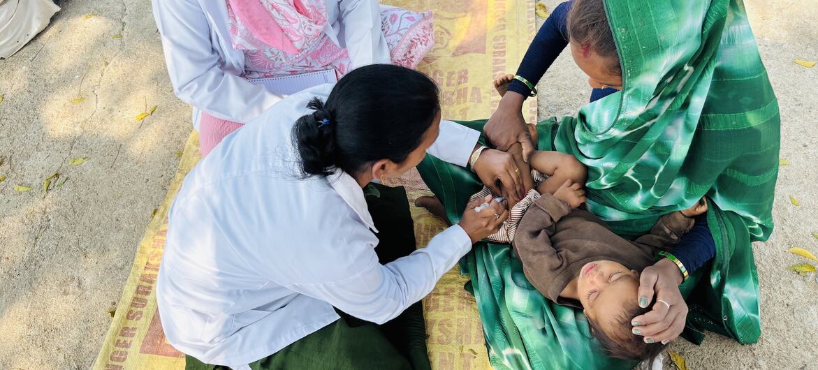सहायक नर्स मिडवाइफ़ दीपा गौर, नियमित टीकाकरण सत्र के दौरान आठ महीने के रौनक आदिवासी को टीका लगाती हुई.