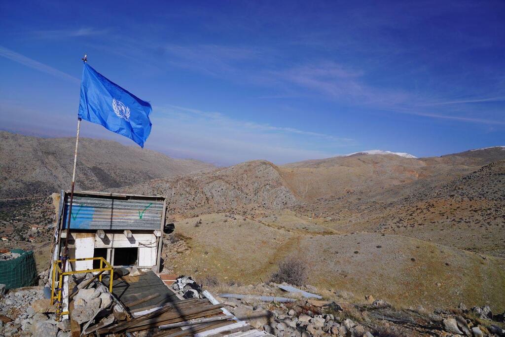 Un avant-poste des forces de la paix de l'UNIFIL avec un drapeau bleu de l'ONU sur le sommet d'une petite structure, situé dans un paysage montagneux rugueux au Liban, près de la ligne bleue.