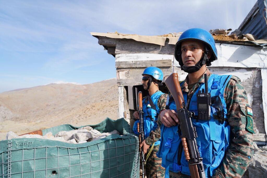 Wanajeshi wawili wa amani wa UNIFIL wakiwa wamevaa kofia na koti za rangi ya bluu wanasimama karibu na jengo lililoharibiwa, wakisimamia Mstari wa Bluu nchini Lebanon.