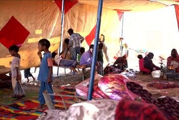 No interior do acampamento de Abu Al Naja, no Sudão, as famílias deslocadas, incluindo mulheres e crianças, descansam e se deslocam sob grandes tendas, destacando a crise humanitária causada pelo conflito em curso.