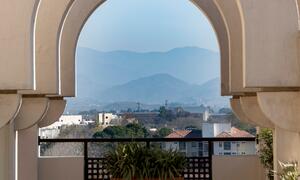 A view of Islamabad, Pakistan, showcasing a series of arches framing a distant mountain range and urban landscape.