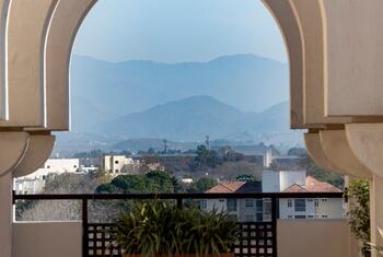 A view of Islamabad, Pakistan, showcasing a series of arches framing a distant mountain range and urban landscape.