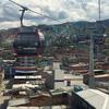 Carros telefônicos TransMiCable viajam sobre as casas de tijolo densamente embaladas do distrito de Ciudad Bolívar em Bogotá, Colômbia, com as montanhas no fundo.