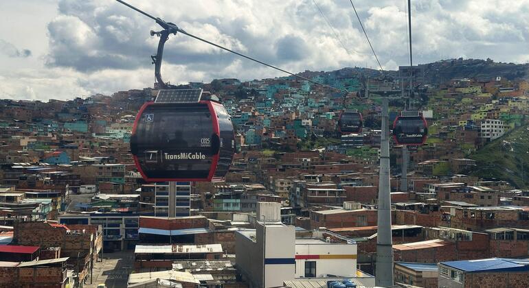 Los teleféricos TransMiCable viajan sobre las casas de ladrillo densamente llenas del distrito de Ciudad Bolívar en Bogotá, Colombia, con las montañas en el fondo.