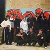 Un grupo de jóvenes colombianos y venezolanos posando juntos frente a un colorido muro de graffiti en el distrito Ciudad Bolívar de Bogotá, Colombia. La imagen captura la integración de la comunidad a través de la danza, destacando la vibrante vida cultural de este barrio urbano.