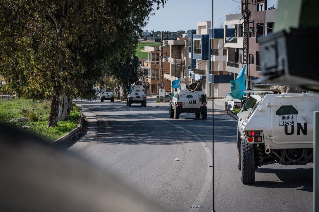 Un convoi de véhicules blindés blancs de l'UNIFIL conduit le long d'une route au Liban, avec des drapeaux de l'ONU visibles.