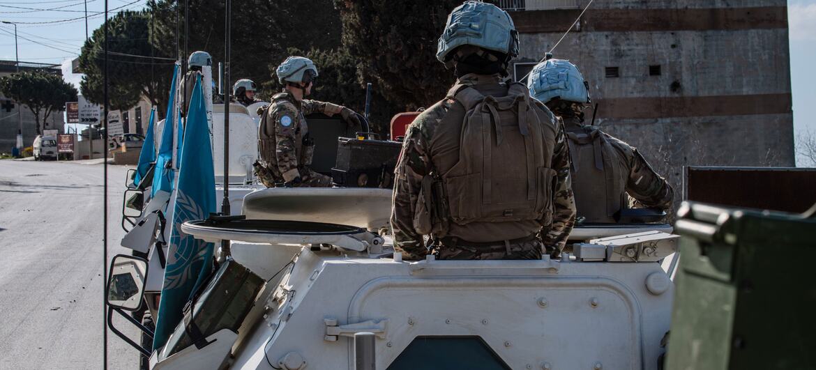 Retrospecto de peacekeepers da UNIFIL com capacetes azuis e uniformes camuflados em um veículo blindado com bandeira da ONU, durante uma operação no Líbano.