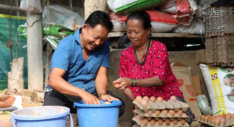 Мужчина и женщина сортируют яйца в картон и ведра на сельском рынке в Бутане.