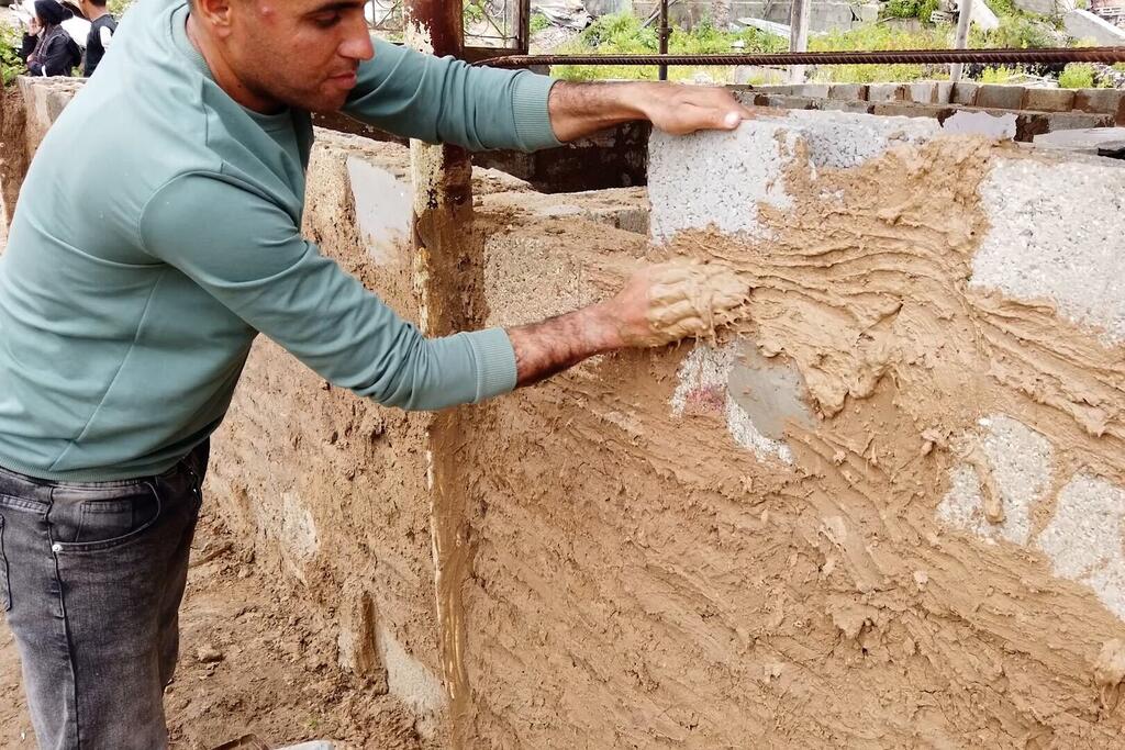 El Sr. Mohammed al-Jathbah está llevando a cabo trabajos de construcción en su nueva casa improvisada, utilizando piedras recuperadas de los escombros de su casa destruida.