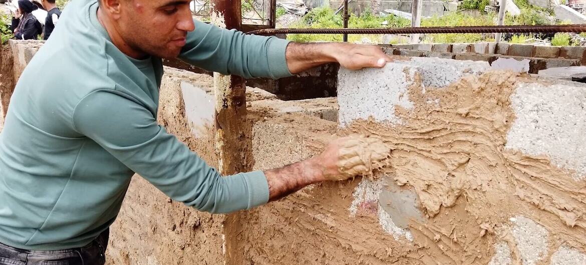 ينفذ السيد محمد الجثبه أعمال بناء في منزله المؤقت الجديد، باستخدام الحجارة التي تم إنقاذها من أنقاض منزله المدمر.