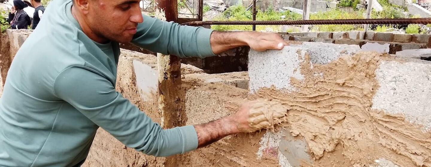 El Sr. Mohammed al-Jathbah está llevando a cabo trabajos de construcción en su nueva casa improvisada, utilizando piedras recuperadas de los escombros de su casa destruida.