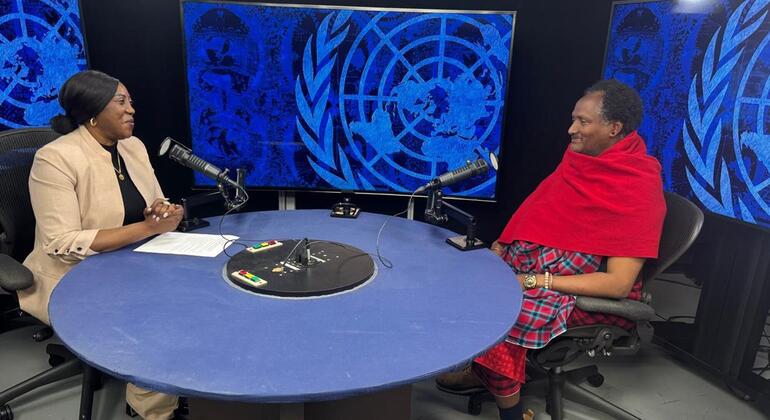 Mwanachama wa UNPFII, Ole Kulet, kutoka Tanzania, anahojiwa na mwanachama wa shirika la Umoja wa Mataifa katika studio yenye nembo za Umoja wa Mataifa nyuma.
