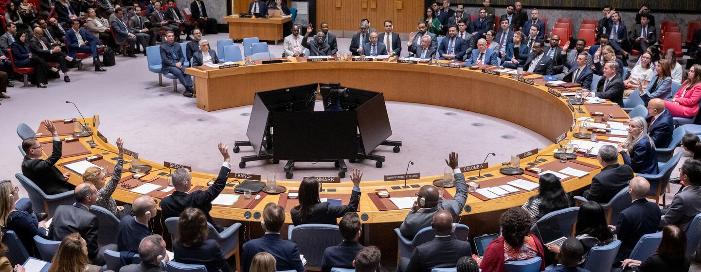 Une photographie grand angle de la salle du Conseil de sécurité des Nations Unies montrant les États membres se réunissant pour discuter de la situation au Moyen-Orient, avec plusieurs délégués levant la main.