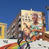 Um grande mural na lateral de um prédio de apartamentos em Zambujal, Portugal, retratando duas mulheres de diferentes etnias. Em primeiro plano, um conjunto de escadas brancas é pintado com um arco-íris e a palavra PAZ.