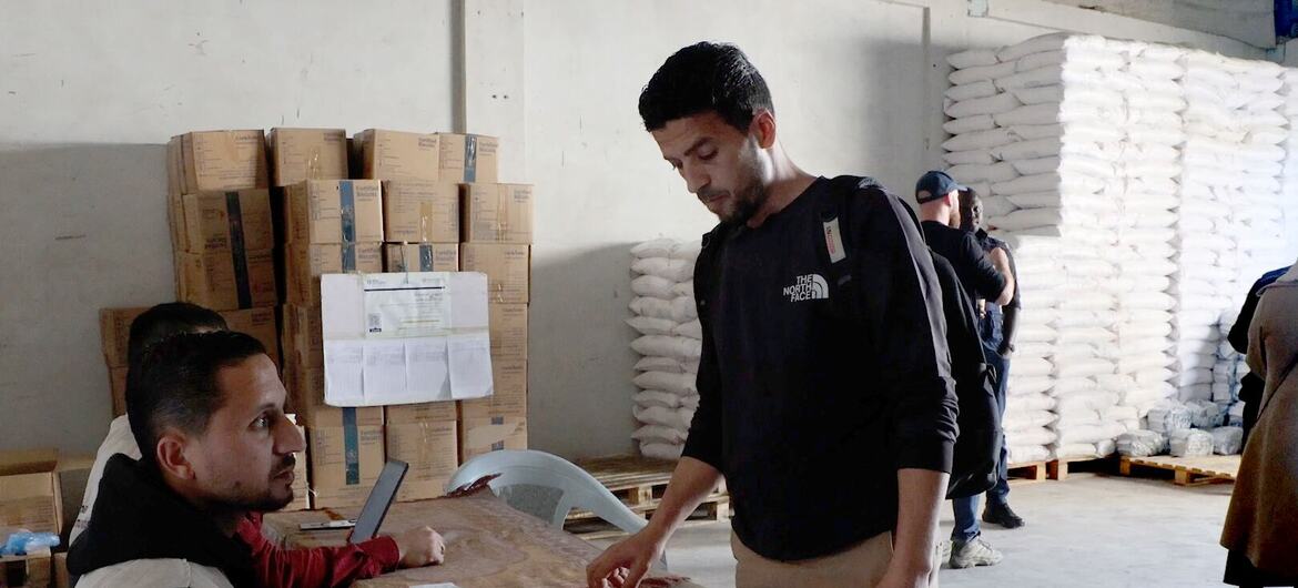 Un travailleur humanitaire du PAM enregistre un bénéficiaire dans un centre de distribution de nourriture dans le camp de réfugiés d'Al-Shati à Gaza, à l'aide d'une tablette.