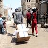 فلسطينيون يحملون صناديق من المساعدات الغذائية على عربات وبيد في شارع في غزة أثناء توزيع من قبل برنامج الأغذية العالمي (WFP).