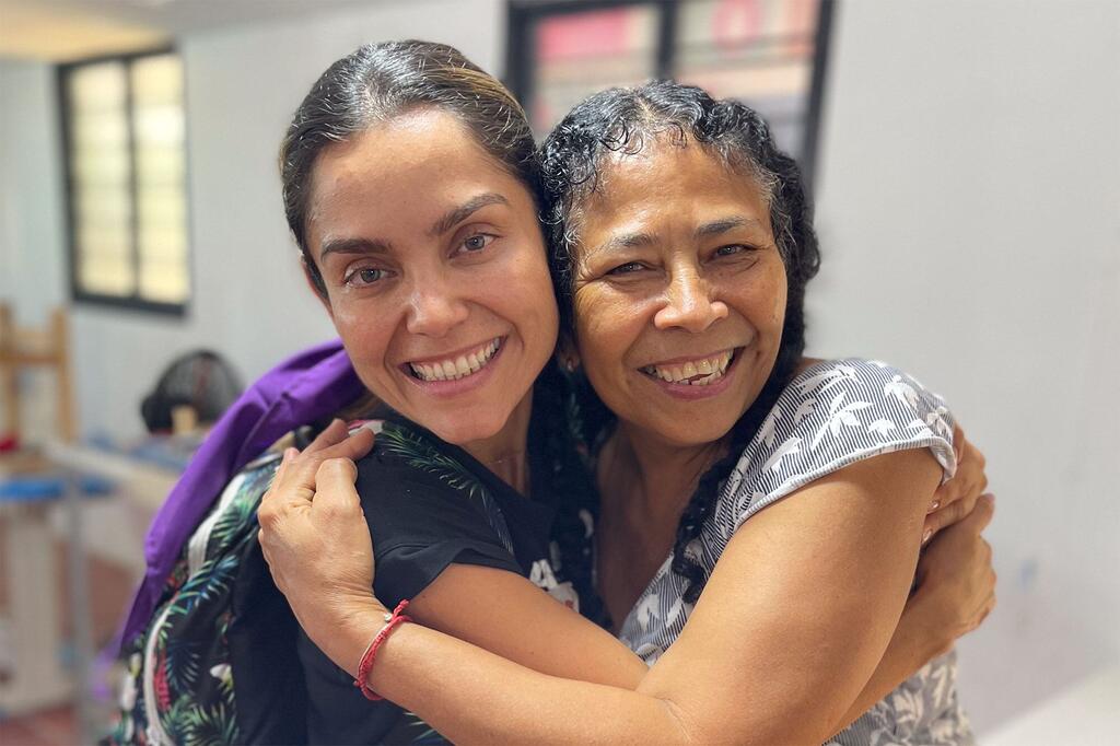 Katerine Avella y Lina Garcés Garcés sonriendo y abrazándose después de completar un curso de confección de prendas en el ETCR en Caño Indio, Colombia, que condujo a la creación de las faldas de la marca Ixora.