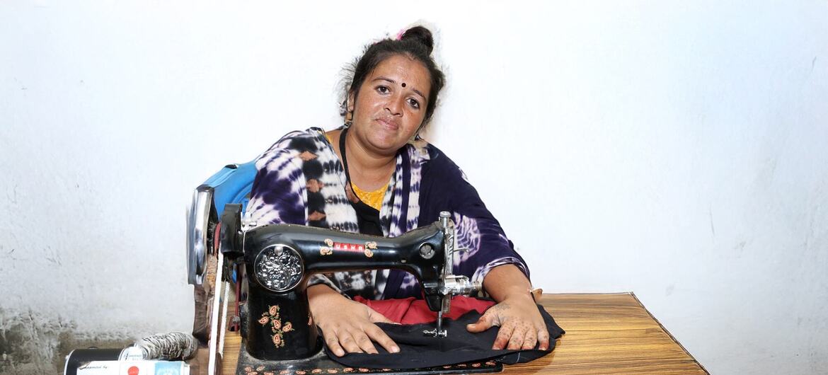 भारत में एक महिला UNDP के सौर कौशल प्रशिक्षण कार्यक्रम के हिस्से के रूप में एक सिलाई मशीन संचालित कर रही है, जिसमें UNDP और SNI के लोगो मेज पर दिखाई देते हैं।