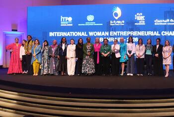 مجموعة من النساء رواد الأعمال تظهر لالتقاط صورة على خشبة المسرح في المسابقة الدولية للمرأة رواد الأعمال 2026 في المنامة، البحرين، مع عرض شعارات الحدث على شاشة كبيرة خلفهن.