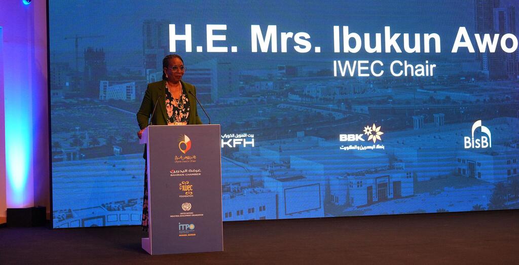 H.E. Bi Ibukun Awo, Mwenyekiti wa IWECC, akitoa hotuba ya msingi katika mkutano wa WEIF2026 huko Bahrain, akiwa amesimama kwenye jukwaa lenye nembo za wadhamini na mandhari ya jiji.