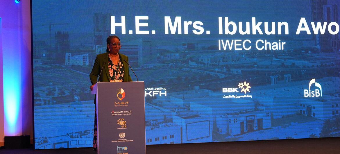 H.E. Mrs. Ibukun Awo, IWECC Chair, delivering a keynote speech at WEIF2026 in Bahrain, standing at a podium with logos of sponsors and a cityscape backdrop.