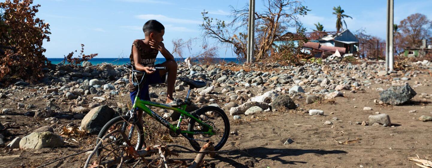 Un jeune garçon est assis sur un vélo vert au milieu des décombres et des débris à Guamá, à Santiago de Cuba, après que l'ouragan Melissa ait causé des dégâts considérables.