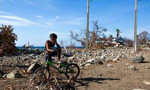 Un niño se sienta en una bicicleta verde en medio de escombros y escombros en Guamá, Santiago de Cuba, después de que el huracán Melissa causara grandes destrucciones.