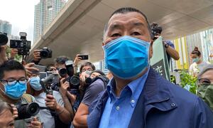 Jimmy Lai, 73-year-old founder of Next Media, wearing a blue face mask, surrounded by reporters and photographers during a court appearance in Hong Kong.