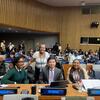 Um grupo de delegados da Namíbia, Mianmar e Moçambique posa para uma foto à mesa de conferências de uma grande sala de reuniões.