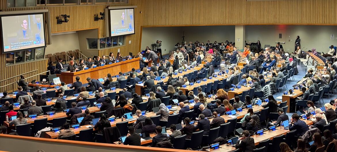 An overhead view of a large international conference hall filled with delegates seated at long tables, attending the 64th Commission for Social Development (CSocD64) meeting at the United Nations.