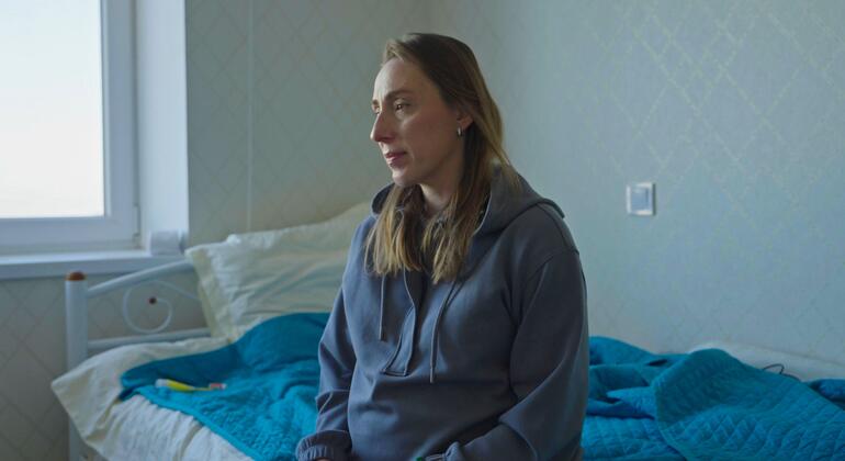 Женщина сидит на больничной койке в Украине, размышляя о проблемах, с которыми сталкиваются беременные женщины и новорожденные в условиях нападений на критически важную инфраструктуру.