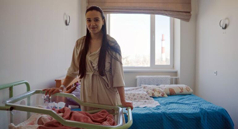 Беременная женщина стоит рядом с новорожденным в инкубаторе внутри роддома в Украине, подчеркивая проблемы, с которыми сталкиваются работники здравоохранения во время продолжающегося конфликта.