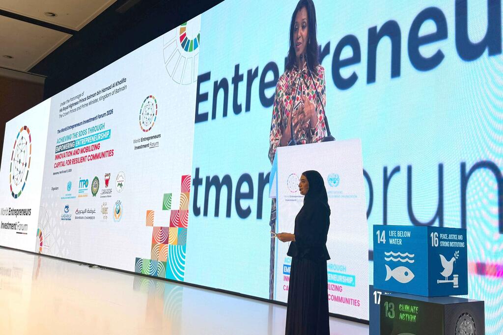 A speaker presents at the World Entrepreneurs Investment Forum 2026 in Manama, Bahrain, with a large screen displaying event logos and Sustainable Development Goals.