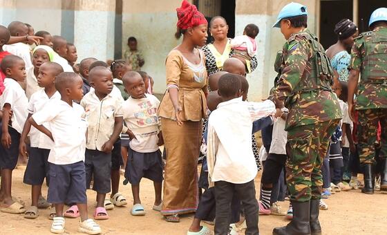 Askari wa kulinda amani wa Umoja wa Mataifa akishirikiana na watoto wakati wa tukio la elimu katika Jamhuri ya Kidemokrasia ya Kongo, sehemu ya ujumbe wa MONUSCO.