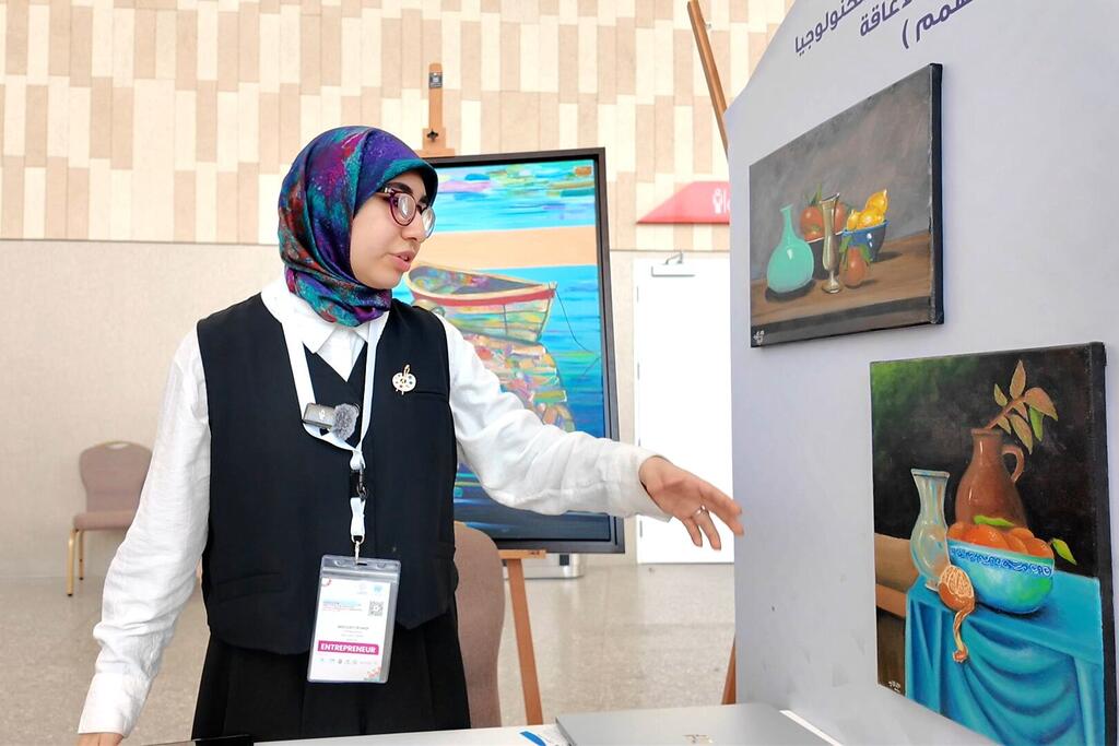 مريم سيد أنور فنانة بصرية، تتحرك تجاه أعمالها الفنية في معرض WEIF2026، حيث أظهرت موهبتها في الحياة الطبيعية والرسومات الصورة بالرغم من عيشها مع إعاقة.