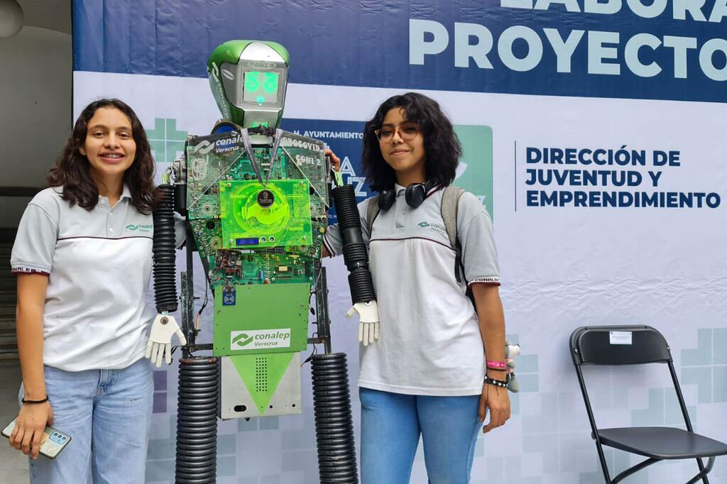 Dos jóvenes mexicanas están junto a un robot que crearon, mostrando su proyecto de ciencia e ingeniería en un evento para jóvenes y emprendedores.