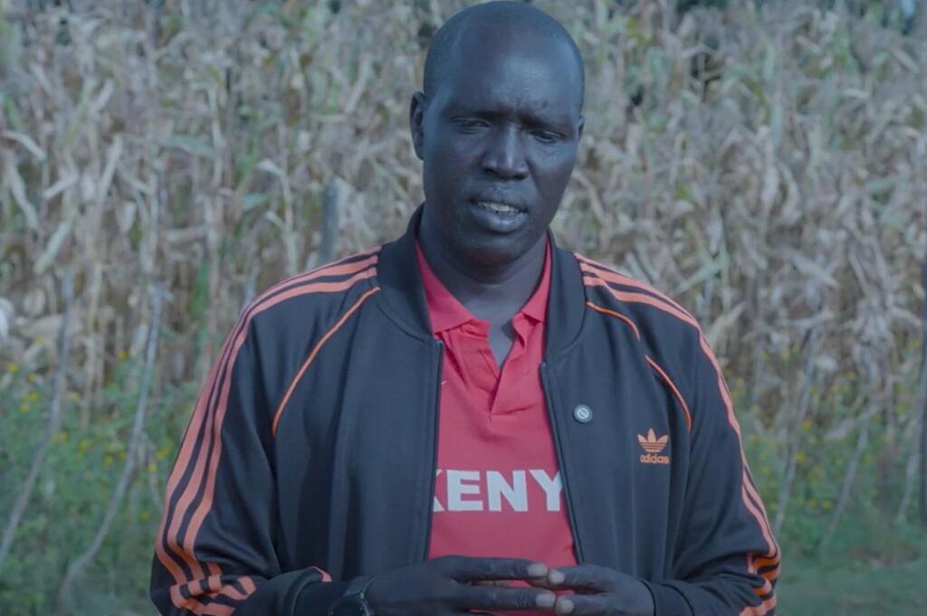 Mwanamume wa Kenya amevaa mavazi ya michezo akizungumza wakati wa mahojiano ya nje yanayohusiana na mipango ya UNFPA ya uhamasishaji dhidi ya GBV.