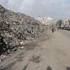 Une grande pile de déchets se dresse dans une rue du marché de Firas, dans la ville de Gaza, avec des gens qui marchent à distance alors que le PNUD et les organisations locales commencent les efforts de nettoyage.