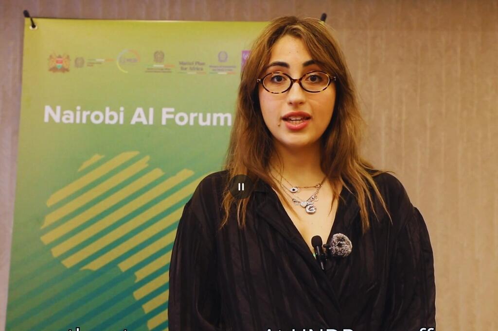 Mwanamke akizungumza katika Jukwaa la Nairobi AI Forum, akiwa na bendera ya kijani inayoonyesha jina la tukio na nembo nyuma.