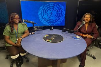 Wanawake weusi wawili wameketi kwenye meza ya mviringo yenye maikrofoni katika studio ya utangazaji, wakiwa na skrini kubwa inayoonyesha nembo ya Umoja wa Mataifa nyuma yao.