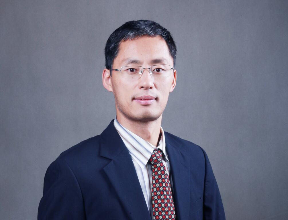 在灰色背景下穿着黑色西装,白色衫和图案带领.