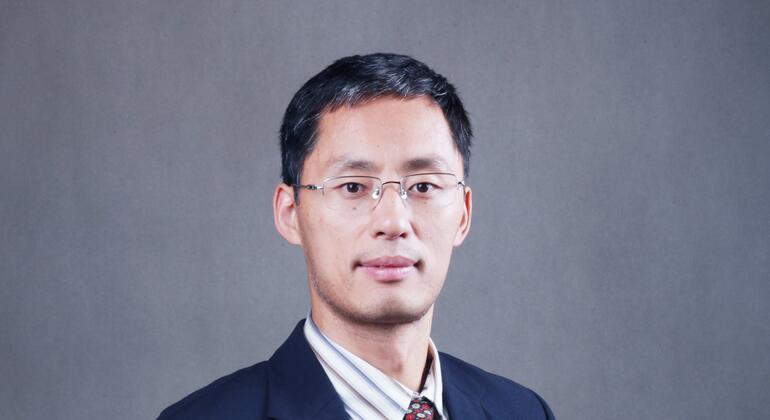 在灰色背景下穿着黑色西装,白色衫和图案带领.