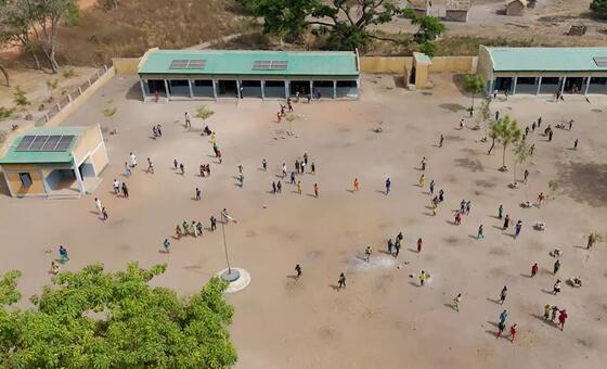 Maono kutoka angani ya shule moja nchini Chad pamoja na watoto wakicheza katika ua, wakiwa na paneli za sola juu ya paa na kwenye jengo lililo karibu.